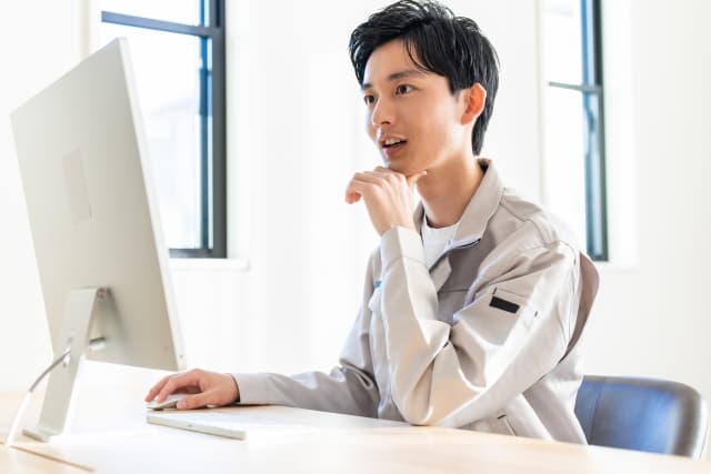 作業着でパソコンに向かう設計担当(イメージ)