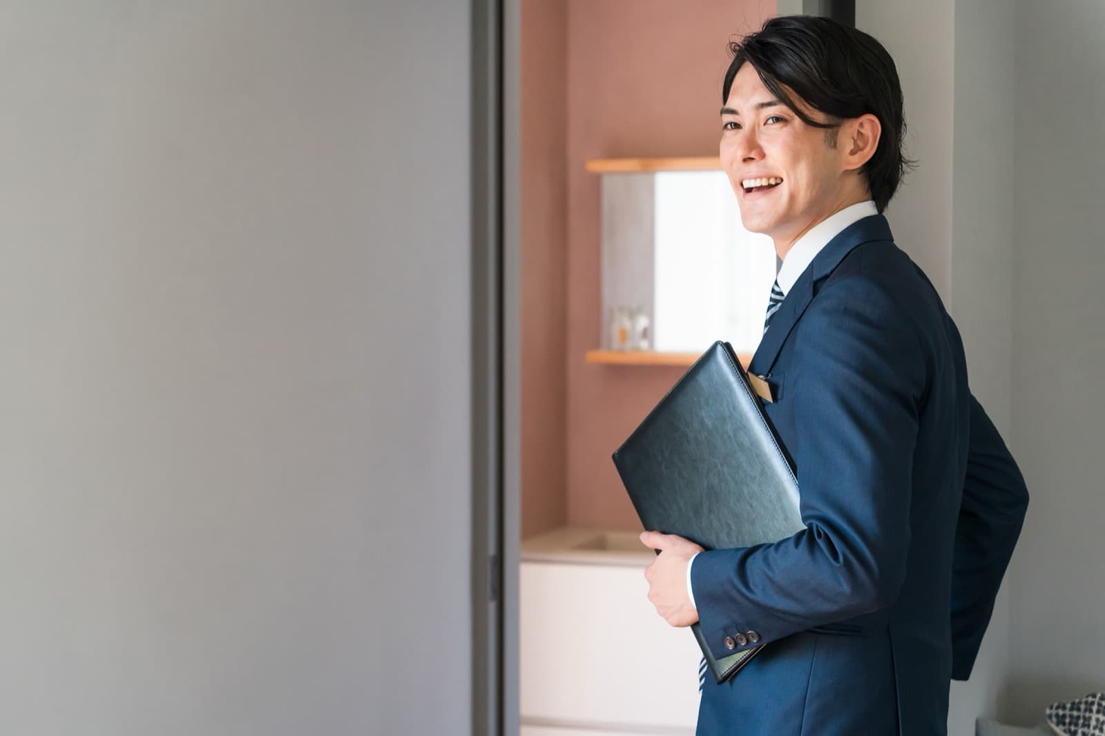 書類を抱えて笑顔で振り返る営業担当(イメージ)